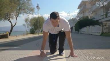 慢动作斯坦尼康拍摄的一个年轻人从蹲开始跑步，每天沿着海滨慢跑
